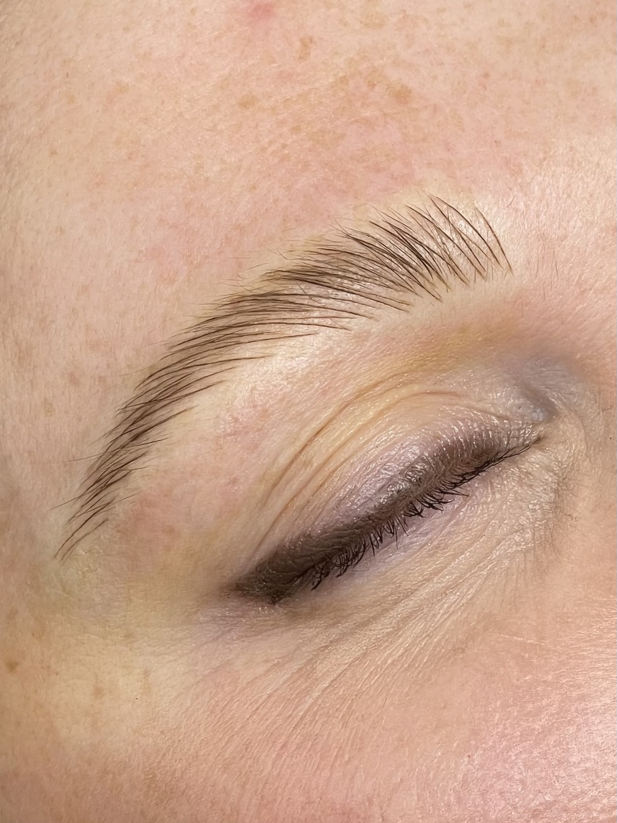 Close-up of a microblading result, showing individual hair strokes forming a soft tapered arch