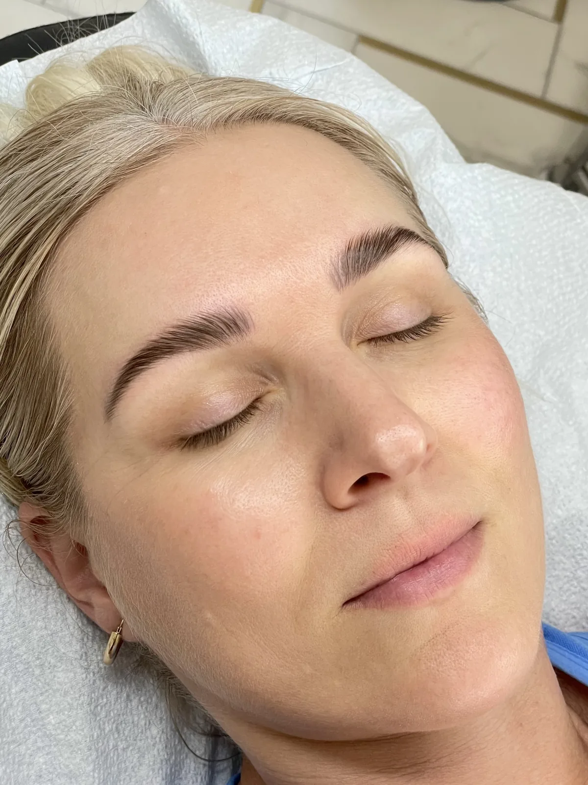 Brow lift and tint on both brows, hairs set upward into a defined arch with a tapered tail