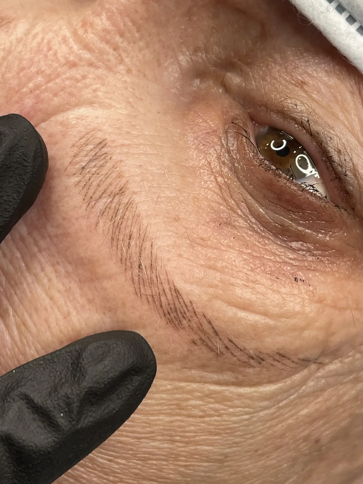 Skin held taut to show crisp healed microblading strokes on mature skin